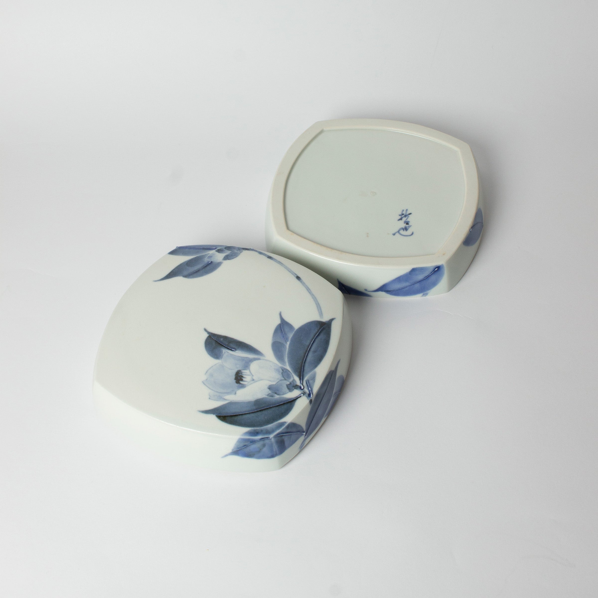 Boîte en porcelaine japonaise ouverte, couvercle posé à côté. Œuvre de Tetsuya Ueda, au motif de camélia en bleu de cobalt.