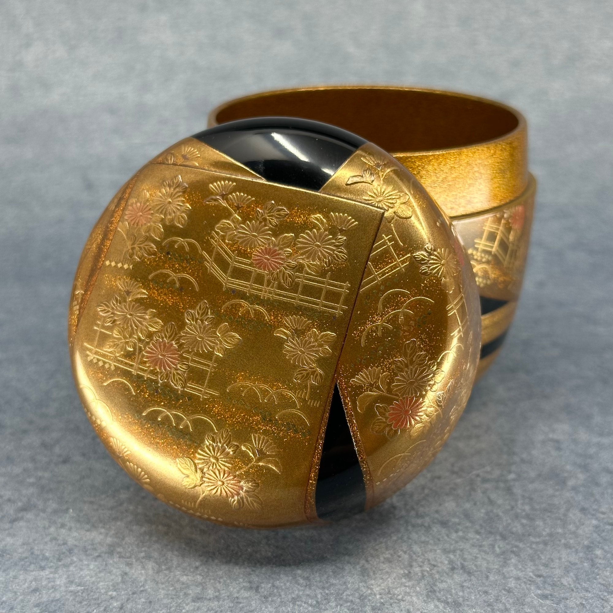 Vue rapprochée du couvercle du natsume révélant le contraste entre l’or lumineux et la profondeur du noir – Atelier Ikiwa